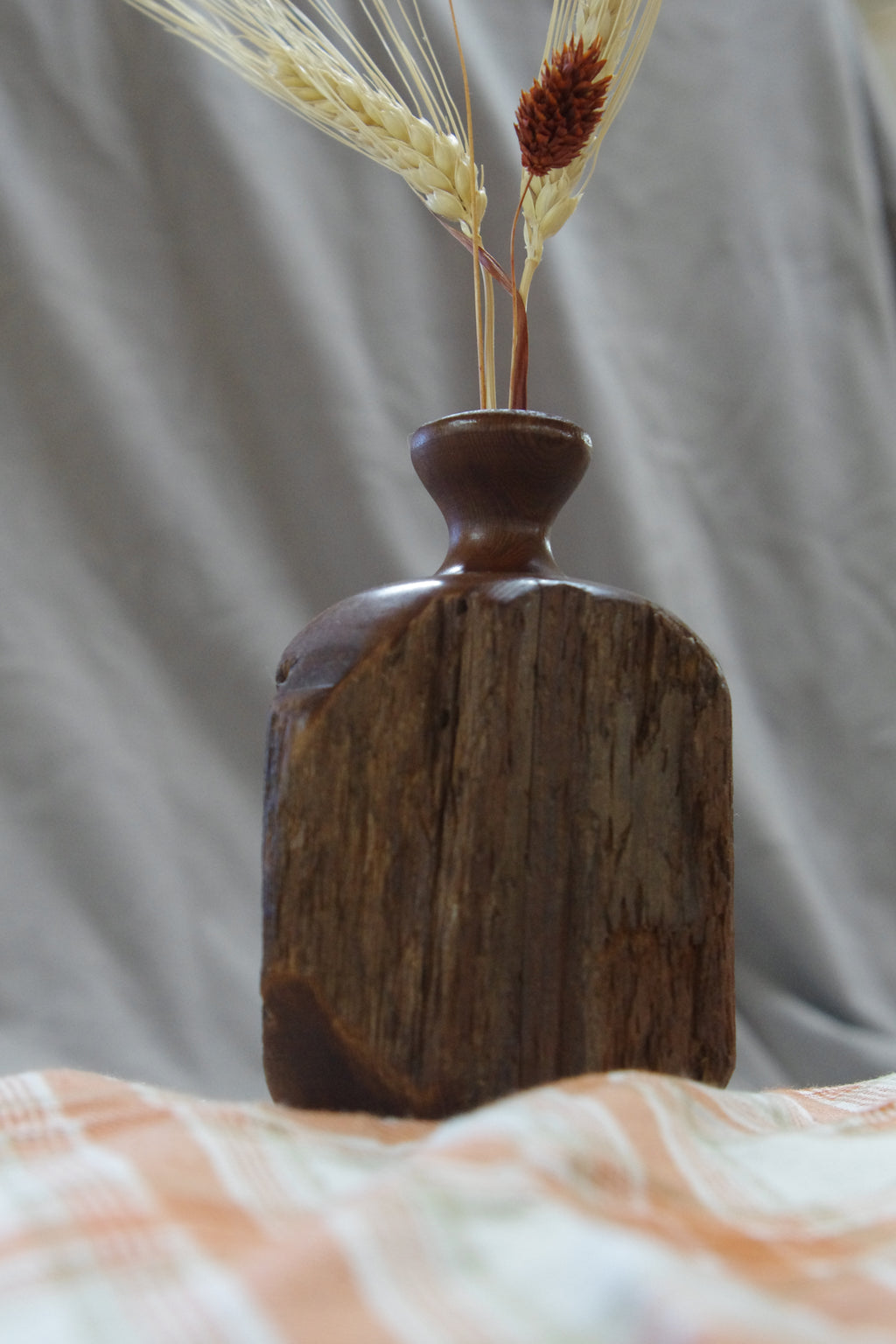 Wooden vase with a textured surface on a soft, blurred background