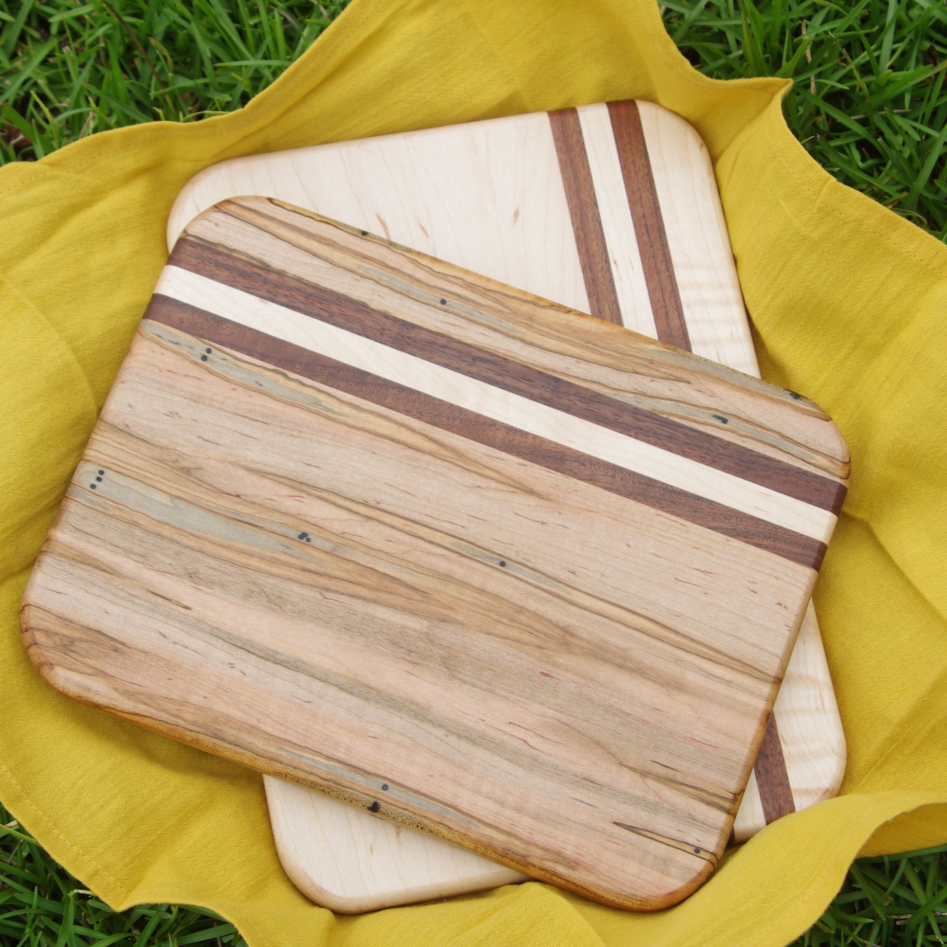 In natural day light. ambrosia maple cutting board with maple and walnut accents on top of a maple cutting board with walnut accents