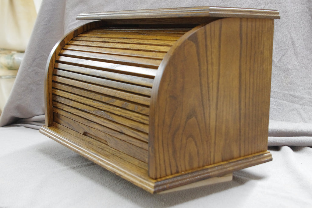 Front of Oak bread box with a roll-top door, crafted from natural oak wood that highlights its beautiful grain. Stained in an darker brown for a rich, inviting look, this bread box adds a warm, rustic touch to your kitchen. The spacious interior helps keep bread and baked goods fresh, while the sturdy construction and classic design offer both style and functionality. A perfect storage solution for keeping bread and other baked goods organized and fresh.