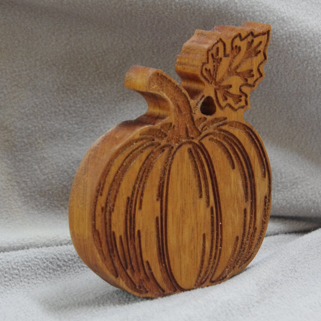 Wooden pumpkin decoration with leaf on a gray fabric background