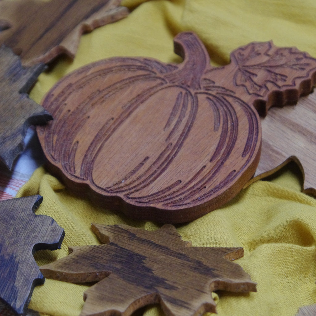 Wooden pumpkin and leaves decor on a yellow fabric background