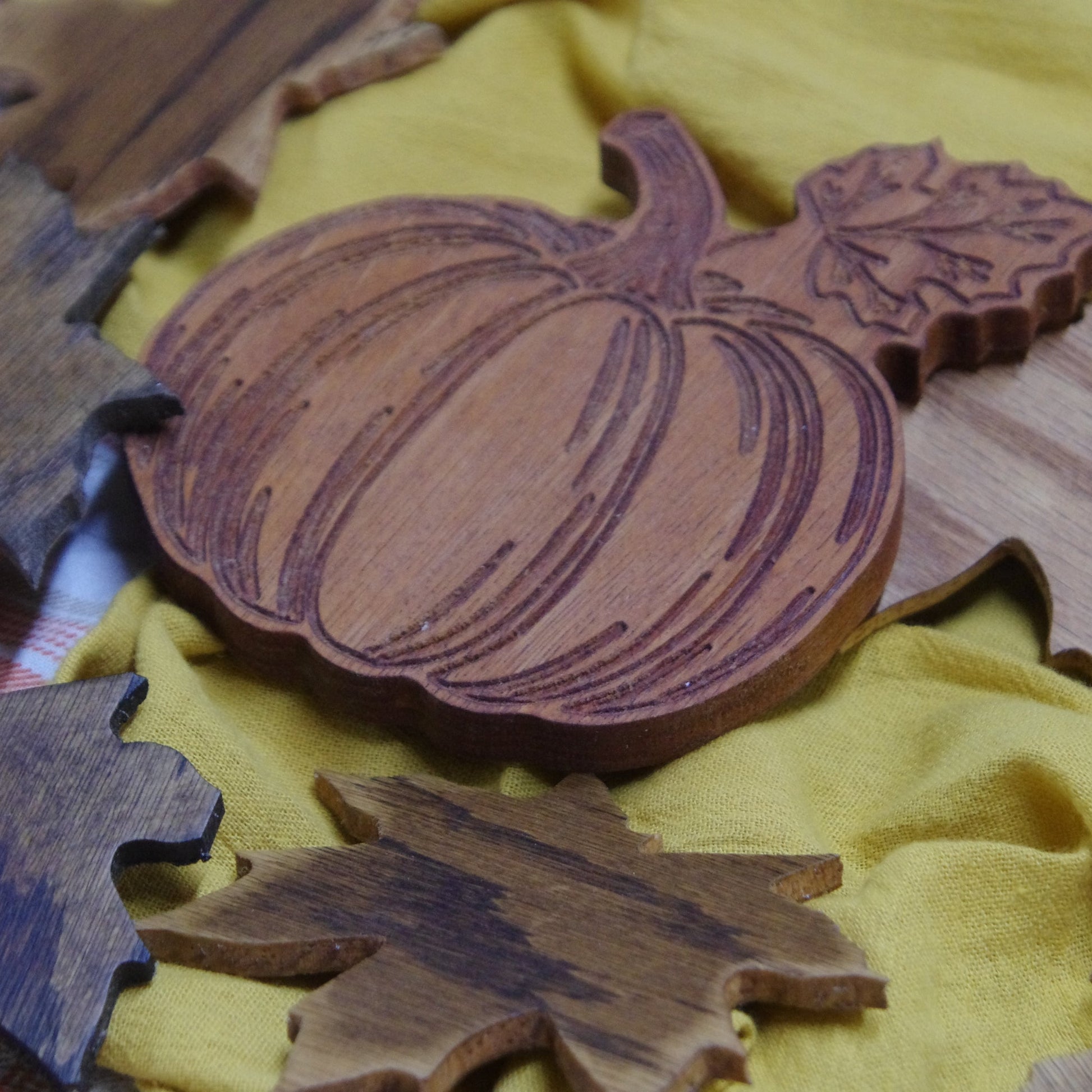 Wooden pumpkin and leaves decor on a yellow fabric background