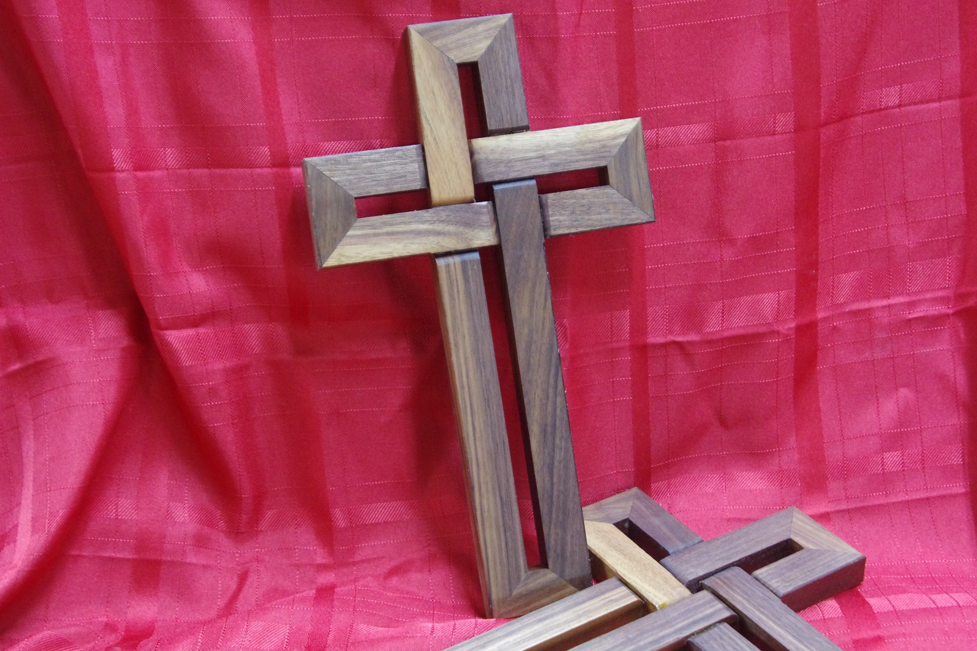 Wooden cross on a red fabric background