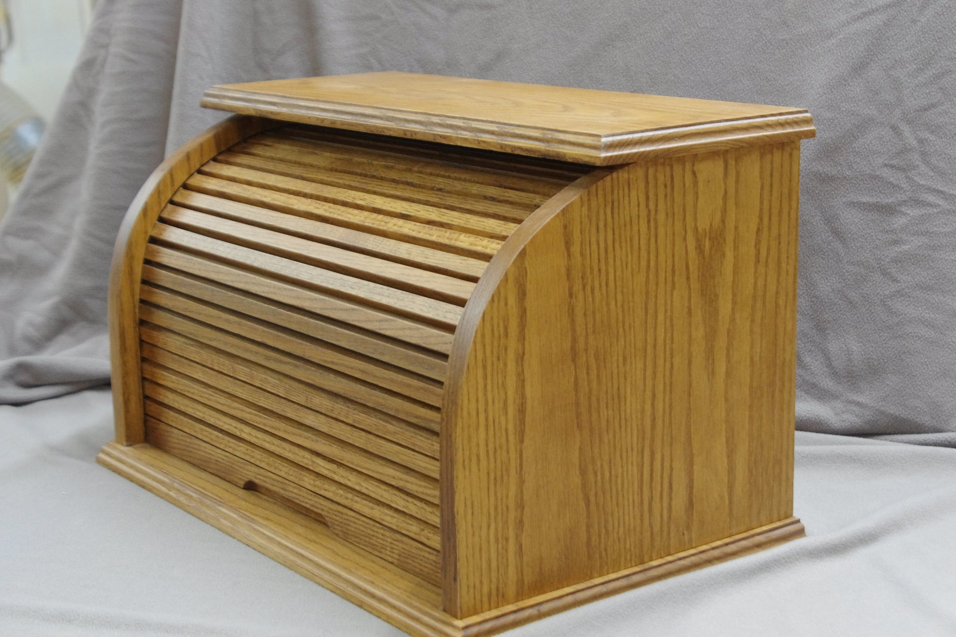 Front of this bread box features a roll-top door, crafted from natural oak wood that highlights its beautiful grain. Stained in a light brown for a rich, inviting look, This bread box adds a warm, rustic touch to your kitchen. The spacious interior helps keep bread and baked goods fresh, while the sturdy construction and classic design offer both style and functionality. A perfect storage solution for keeping bread and other baked goods organized and fresh.
Stain is Early American.