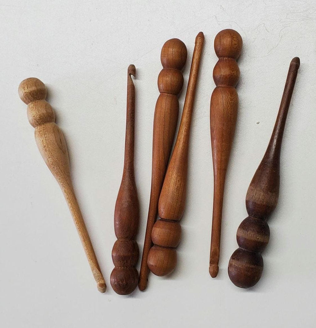 Hand-turned 5mm crochet hook made from natural hardwood, available in maple, cherry, or walnut. The hook features an ergonomic handle and a polished, smooth finish that enhances the unique grain and color of the wood. Maple presents a light, creamy tone; cherry offers a warm reddish hue; and walnut shows a deep, rich brown. Each hook is individually crafted, highlighting the artistry and natural beauty of the selected hardwood.