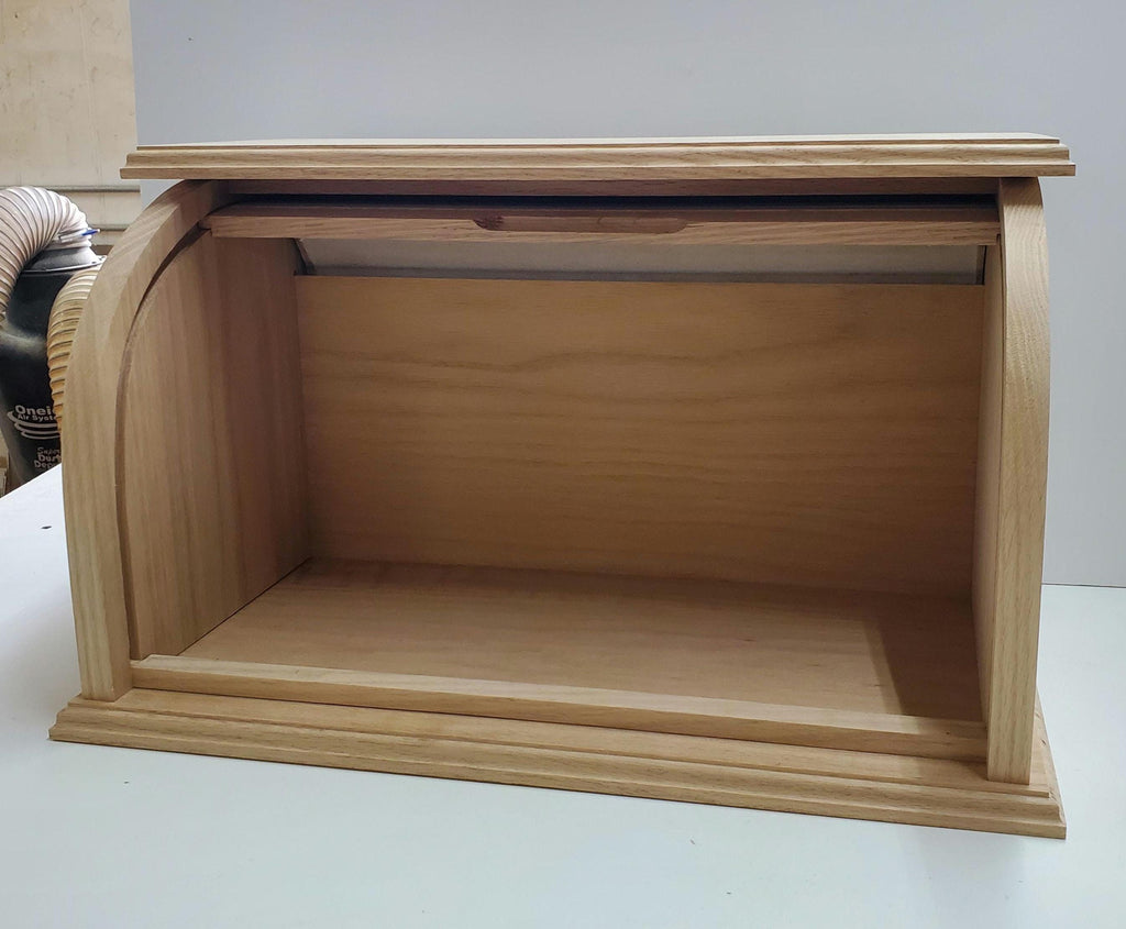 Oak bread box with a roll-top door, shown from the front with the door open to reveal a spacious interior. The natural oak wood showcases a beautiful grain pattern, offering both style and functionality. Perfect for keeping bread and baked goods fresh, while adding a warm, rustic charm to your kitchen. Ideal for customizing with a preferred stain to add a personal touch.