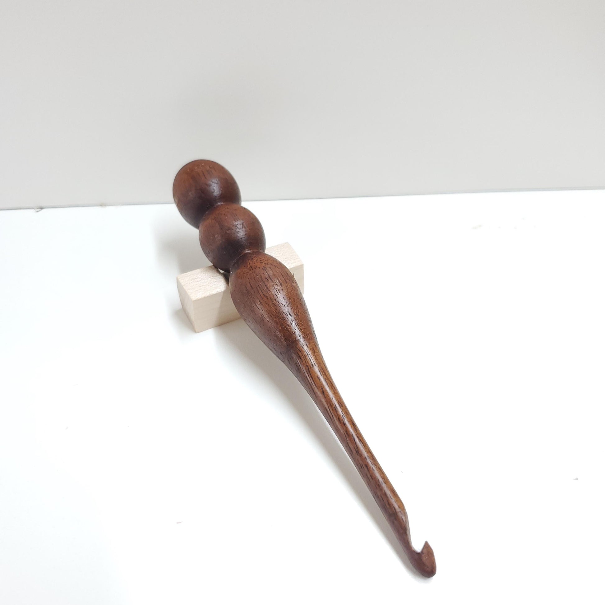 Crafted from rich, dark walnut, this 5mm crochet hook is individually hand-turned to highlight the wood’s stunning natural grain and warm, deep hues. Each hook is uniquely shaped and polished for a smooth, comfortable grip, combining functional elegance with artisanal craftsmanship. While more walnut hooks will be made, no two are exactly alike—each one carries its own distinct character.