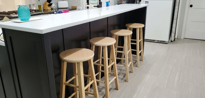 Kitchen island with stools in a modern kitchen setting with a black painted oak tiered island with white countertops