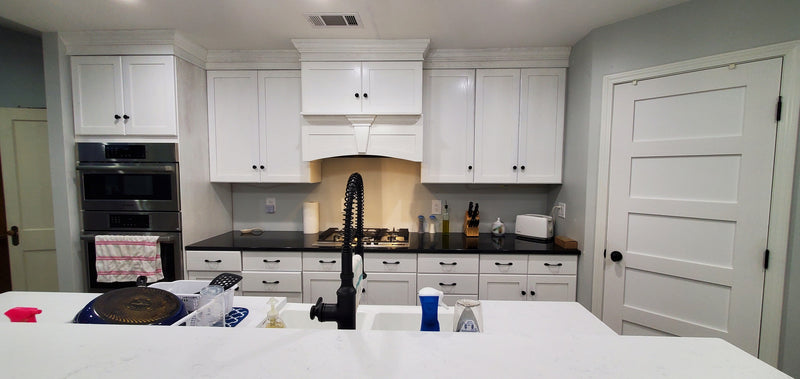 kitchen with white cabinets, black countertops, and stainless steel appliances with tiered island.